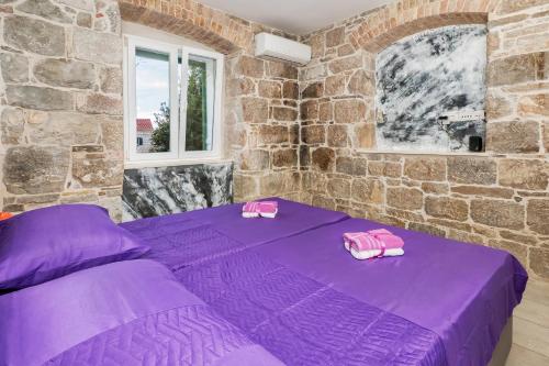a purple bed in a room with a stone wall at Tamaria in Split