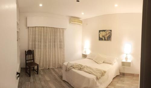 1 dormitorio blanco con 1 cama y 1 silla en La Recalada Departamentos en Concepción del Uruguay