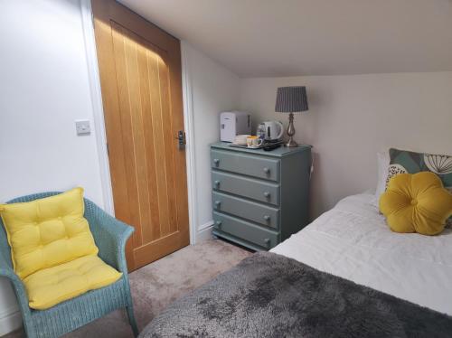 1 dormitorio con cama, silla y vestidor en Pleasant streams Barn en St Austell