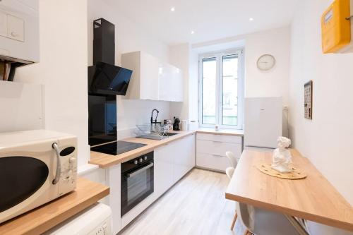 - une cuisine blanche avec une table et un four micro-ondes dans l'établissement Appartement entièrement rénové et cosy avec jardin, à Mulhouse