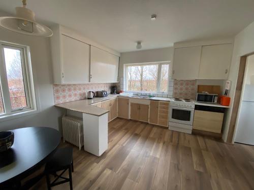 a kitchen with white cabinets and a table in it at Álftártunga Farm Guesthouse in Borgarnes