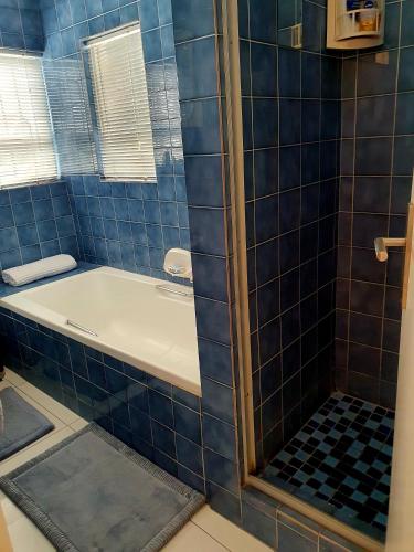 a blue tiled bathroom with a bath tub at La Grace Executive Guesthouse in Amsterdamhoek
