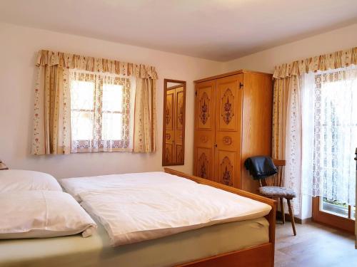 1 dormitorio con 1 cama grande y 2 ventanas en Haus Brandstein Ferienwohnungen en Ramsau