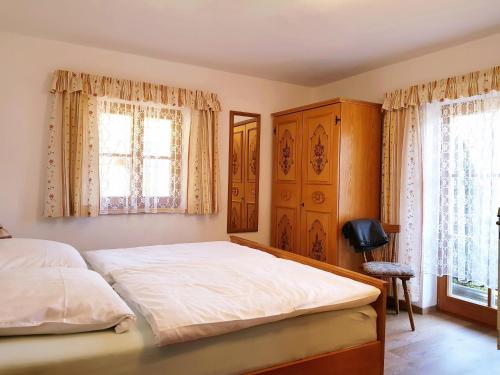 a bedroom with a large bed and two windows at Haus Brandstein Ferienwohnungen in Ramsau