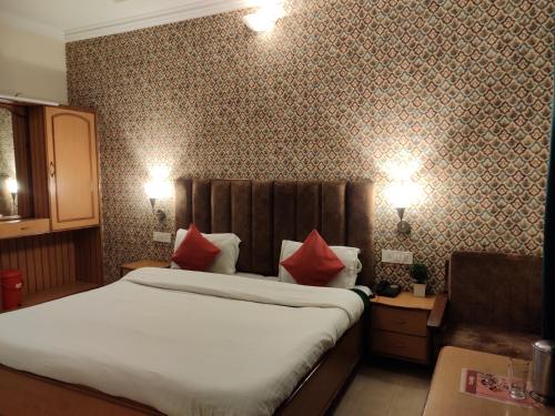 a bedroom with a large bed with red pillows at Hotel Royal in Chamba
