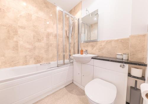 a bathroom with a toilet and a sink and a tub at 7 Greta Grove House in Keswick