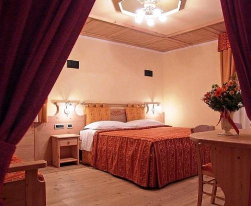 een slaapkamer met een bed en een tafel met bloemen bij Jolly B&B - Affittacamere in Dimaro
