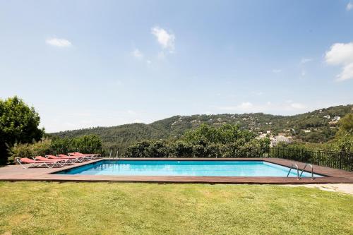 a swimming pool with chairs and a mountain in the background at Can Borrell Villa Carmen in Castellar
