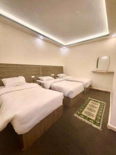 a hotel room with three beds with white sheets at RoadHouse - Petra in Wadi Musa