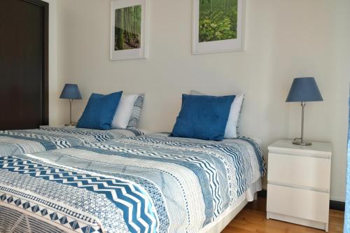 two beds with blue pillows in a white room at Capelas Garden in Capelas