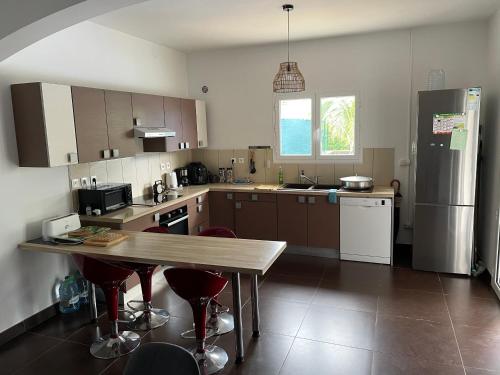 a kitchen with a wooden table and a refrigerator at Villa CoCos Citrons - 5 Chambres - Piscine - Saint Gilles in Saint-Gilles-les Hauts