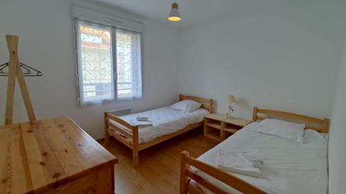 ein Schlafzimmer mit zwei Betten und einem Tisch und einem Fenster in der Unterkunft L'échappée in Fort-Mahon-Plage