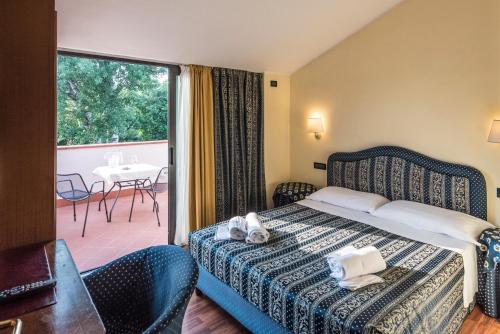 シルミオーネにあるYachting Hotel Mistralのベッドとバルコニー付きのホテルルーム