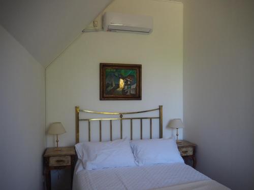 1 cama en un dormitorio con 2 mesas y una foto en la pared en Villa Victoria Lodge en Maipú