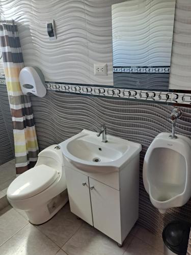 a bathroom with a toilet and a sink and a urinal at Maychu's Albergue in Chincheros