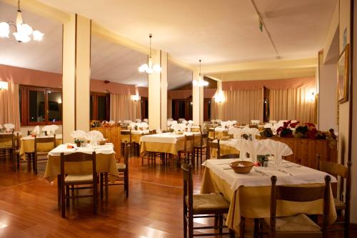 Prati di TivoにあるHotel Gran Sassoの白いテーブルクロスのテーブルと椅子が備わるレストラン