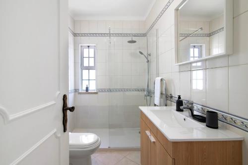 a white bathroom with a sink and a toilet at Villa Galé in Guia
