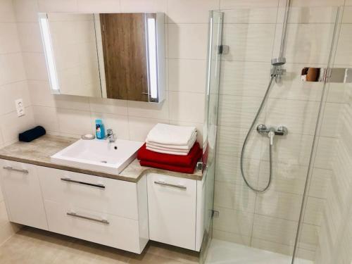 ein weißes Bad mit einer Dusche, einem Waschbecken und einer Dusche in der Unterkunft Admiral Lakeside Luxury Apartment in Siófok