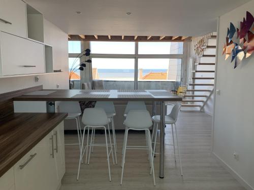 une cuisine avec un grand îlot avec des tabourets blancs dans l'établissement Fort-Mahon-Plage: Duplex 2 chambres, parking, balcon, plage à proximité - FR-1-482-86, à Fort-Mahon-Plage