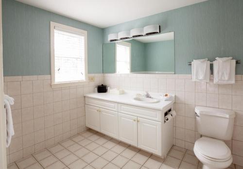 een badkamer met een wastafel, een toilet en een spiegel bij Blue Rock Resort in South Yarmouth