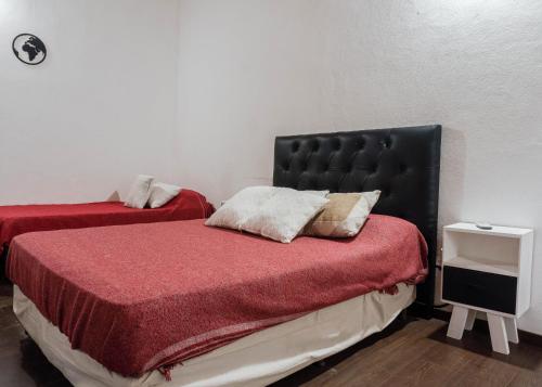 a bedroom with two beds with red sheets and a black headboard at Complejo Yaguareté in Corrientes