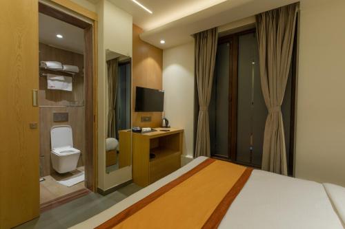 a bedroom with a bed and a toilet and a television at Indus Suites in Nagpur