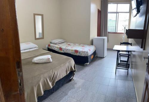 a room with two beds and a table and a desk at Hotel Fortaleza Manaus in Manaus