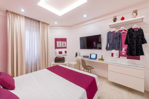 a bedroom with a bed and a desk and a tv at I Mori dell’Etna in Giardini Naxos