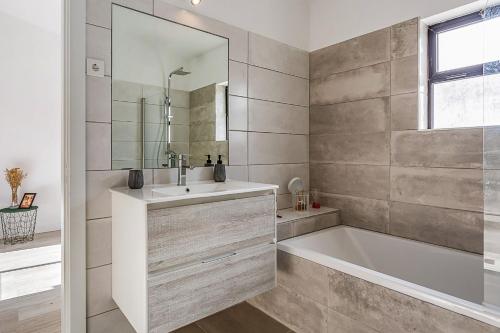 y baño con bañera, lavabo y espejo. en Sunny Duplex W/ Pool & Balcony by LovelyStay, en Carvoeiro