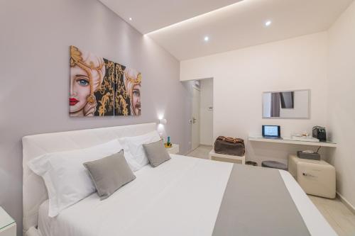 a white bedroom with a white bed and a painting at I Mori dell’Etna in Giardini Naxos
