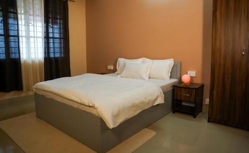 - une chambre dotée d'un grand lit avec des draps et des oreillers blancs dans l'établissement Yellow Sapphire, Premium Sikkimese Homestay, à Gangtok