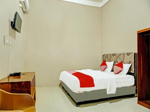 Dormitorio con cama, escritorio y TV en OYO 92386 Homestay Juwita Perdana Syariah, 