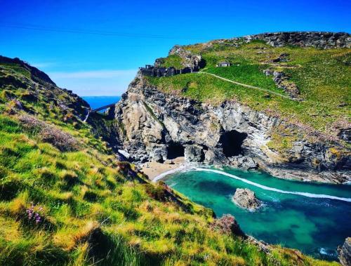 a view of a beach with a cave on a cliff at The little post house. A perfect village retreat, with stunning views. in Boscastle