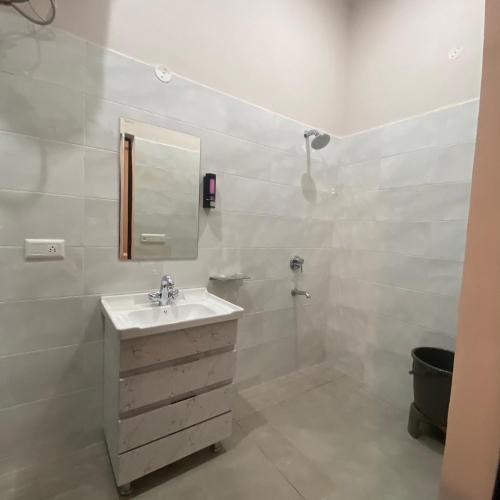 a white bathroom with a sink and a mirror at Wellawing Residency in Ludhiana