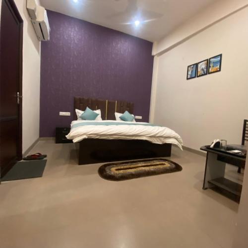 a bedroom with a bed with a purple wall at Wellawing Residency in Ludhiana