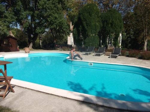 un homme assis dans une chaise à côté d'une piscine dans l'établissement Manoir Larcouillet, à Merles