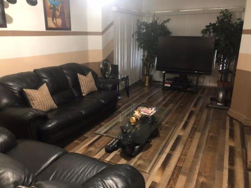 a living room with a leather couch and a flat screen tv at A Hidden Gem, approx 15 mins to downtown Chicago! in Chicago
