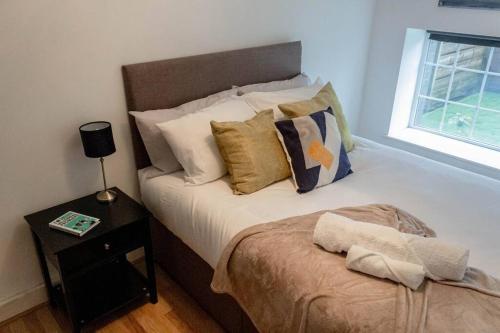 1 dormitorio con cama con almohadas y mesa en Cozy and Modern 2-bed apartment, en Swansea