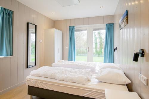 een slaapkamer met 2 bedden, blauwe gordijnen en een raam bij Vakantiehuis Vicky - Julianadorp aan Zee in Julianadorp