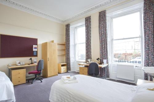 a hotel room with two beds and desks and windows at McIntosh Hall Campus Accommodation in St Andrews