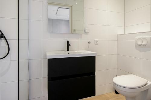 een witte badkamer met een wastafel en een toilet bij Vakantiehuis Vicky - Julianadorp aan Zee in Julianadorp