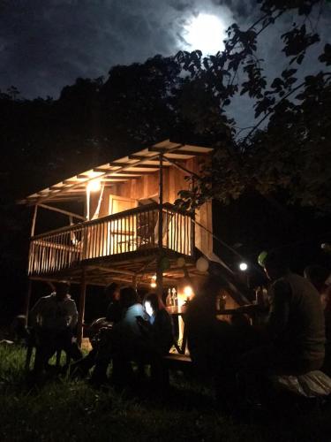 a group of people sitting in front of a house at night at Rumi Wilco Ecolodge & Nature Reserve-Cabañas & Camping in Vilcabamba