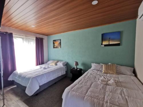 1 dormitorio con 2 camas y TV en la pared en Casa Luna, espacio moderno y acogedor, en Liberia