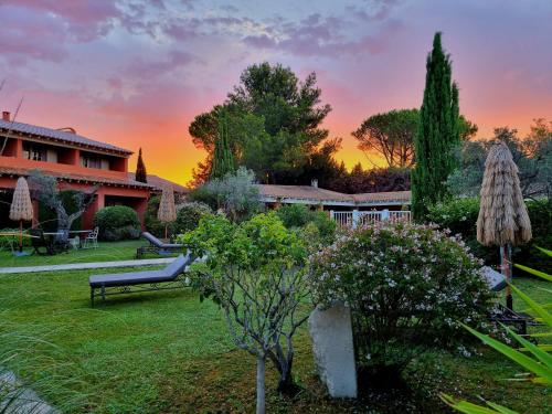 einen Garten mit einer Bank und Bäumen sowie ein Gebäude in der Unterkunft Castillon Des Baux in Maussane-les-Alpilles