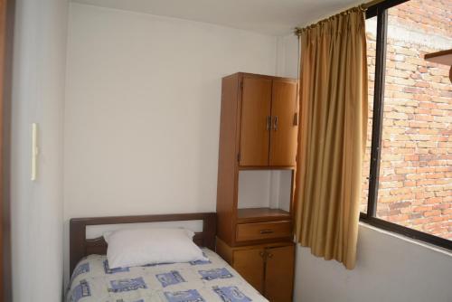 1 dormitorio con 1 cama, armario y ventana en The Quito Guest House with Yellow Balconies for Travellers, en Quito