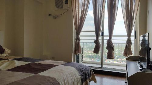 a bedroom with a bed and a large window at Infina Towers Affordable staycation in Manila