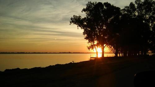 a sunset over a body of water with trees at La casita en San Miguel del Monte in San Miguel del Monte