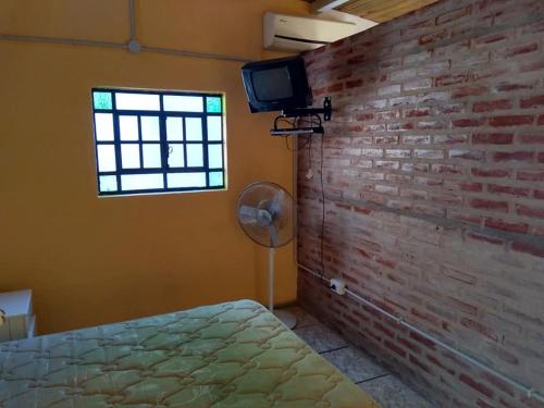 una camera da letto con una parete in mattoni, un ventilatore e una finestra di La casita en San Miguel del Monte a San Miguel del Monte