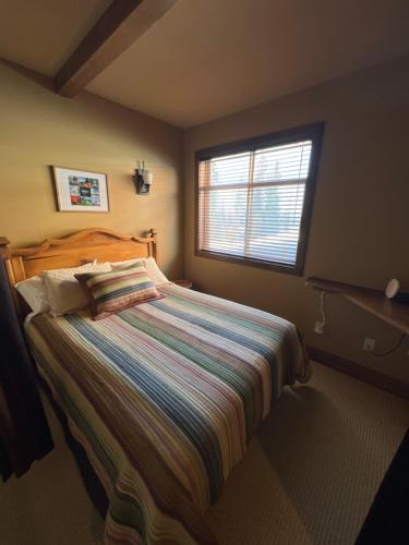 Un dormitorio con una cama grande con ventana. en Magical Views at Southpoint Big White! Best Location!, en Big White