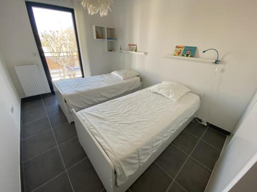 deux lits dans une petite pièce avec une fenêtre dans l'établissement Bel appartement en centre-ville d'Arcachon, résidence récente, proche plages, pour 4 personnes - FR-1-474-185, à Arcachon